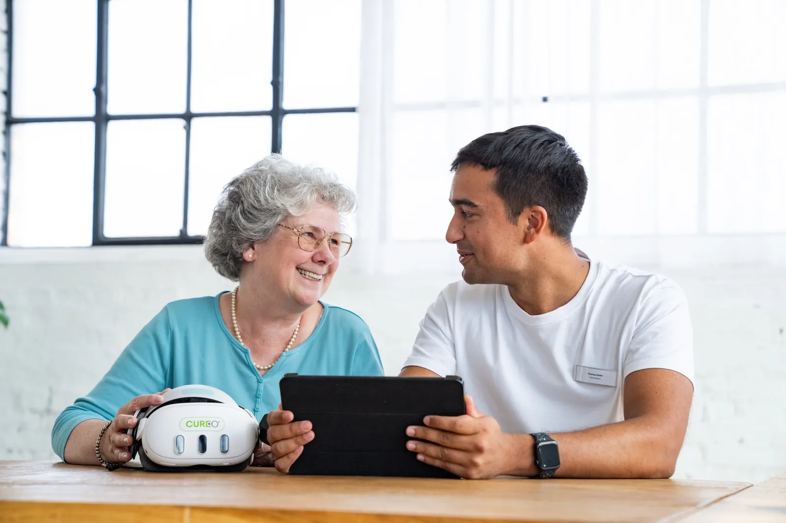A therapist and a patient reviewing a CUREO session on a tablet